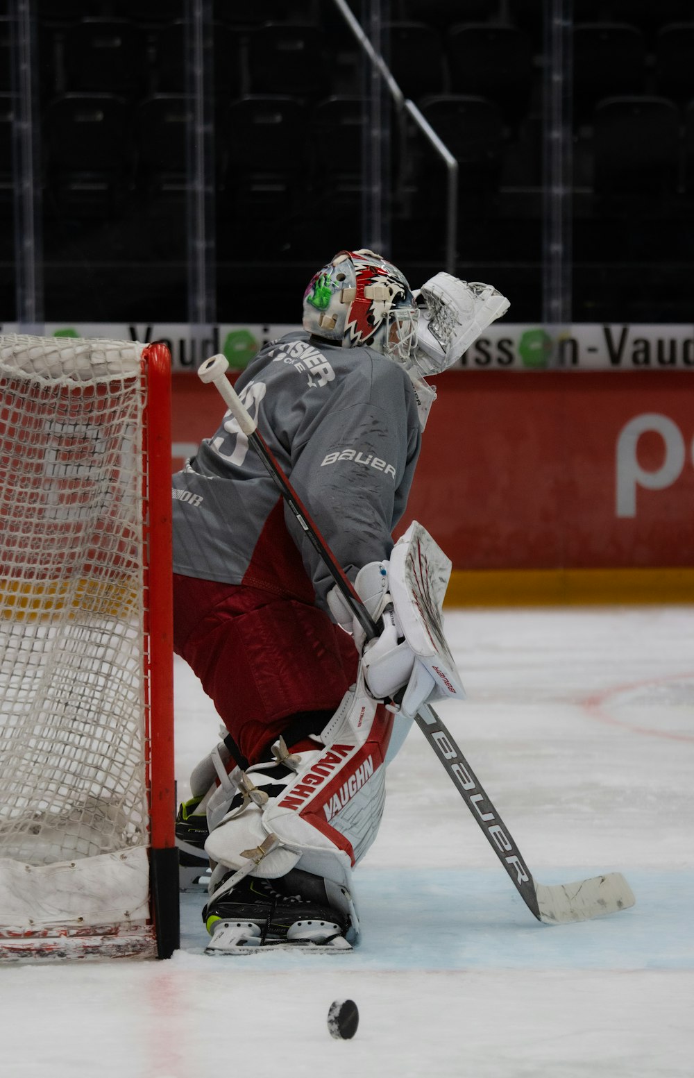 a hockey goalie in a grey jersey and red pants