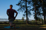 A person stretching their knee gently on a park bench, early morning light casting soft shadows.