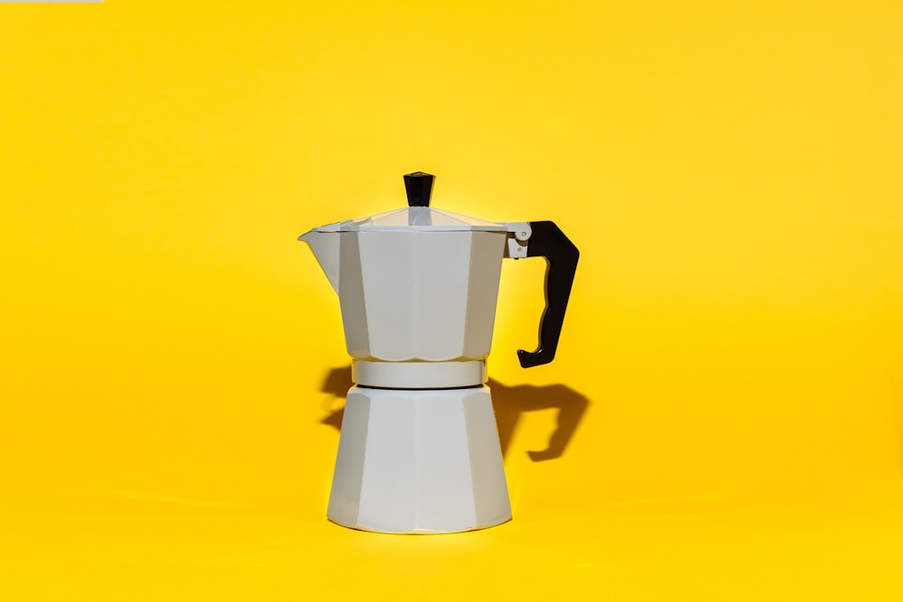 a stove top coffee maker on a yellow background
