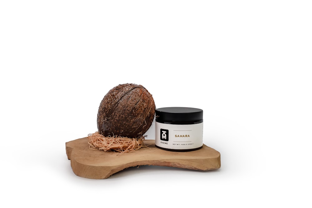 a coconut sitting on top of a wooden board next to a jar of cream