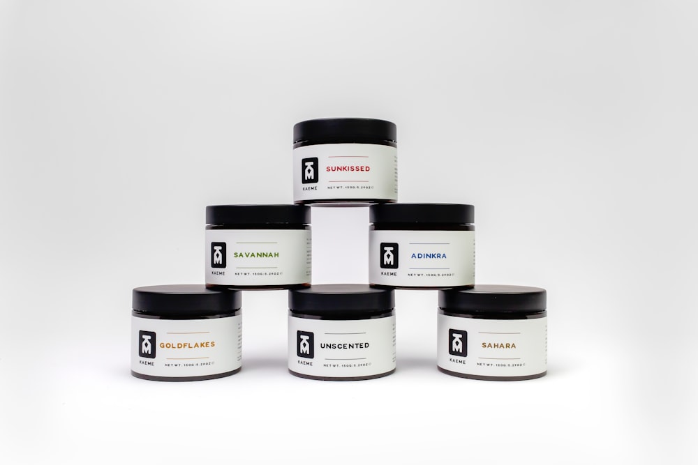 a group of five jars of body butter on a white background