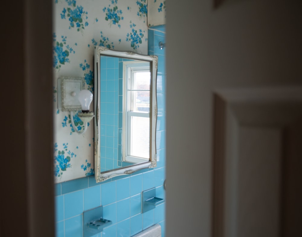 a blue tiled bathroom with a mirror and sink