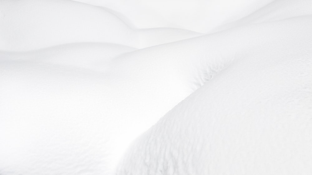 un letto coperto di neve con lenzuola e cuscini bianchi