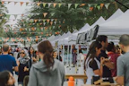 Vibrant outdoor hemp market scene with smiling people browsing stalls under string lights.