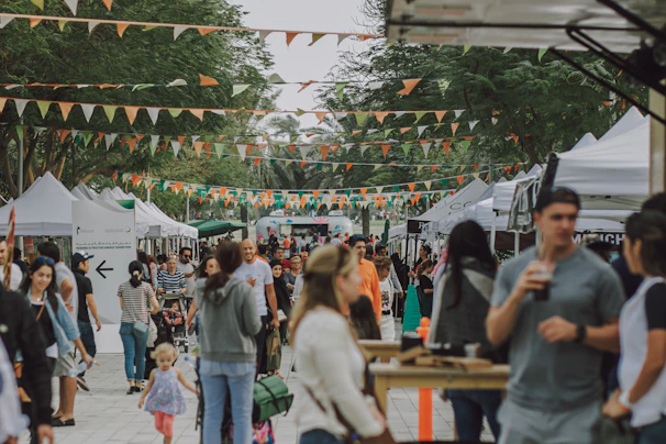 A top-down shot of a bustling outdoor market, colorful tents and crowds creating a lively mosaic.
