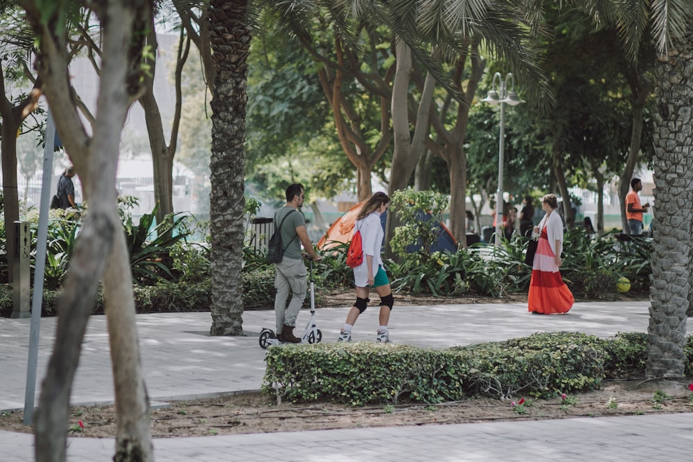 a group of people walking down a sidewalk next to trees