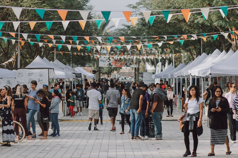 a crowd of people walking around a street next to tents