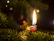 A cozy living room corner softly lit by a glowing green and white candle with a hint of yellow.