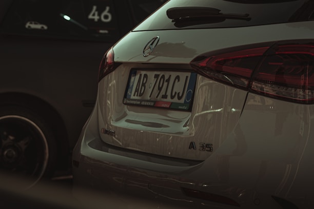 The rear view of a white Mercedes-Benz A35 AMG parked next to another vehicle. The vehicle's license plate is visible, and the Mercedes-Benz logo is prominently displayed. The taillights are sleek and modern, matching the car's sporty aesthetic.