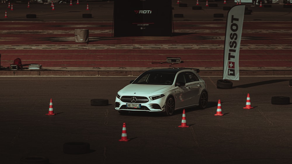 a white car parked in a parking lot next to orange cones