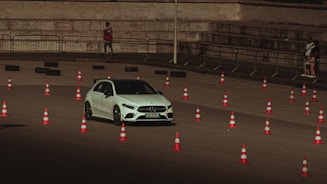 a white car driving past orange and white cones
