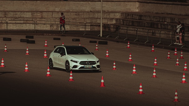 a white car driving past orange and white cones