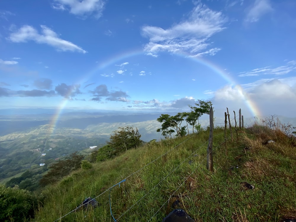 a rainbow is seen over a grassy hill