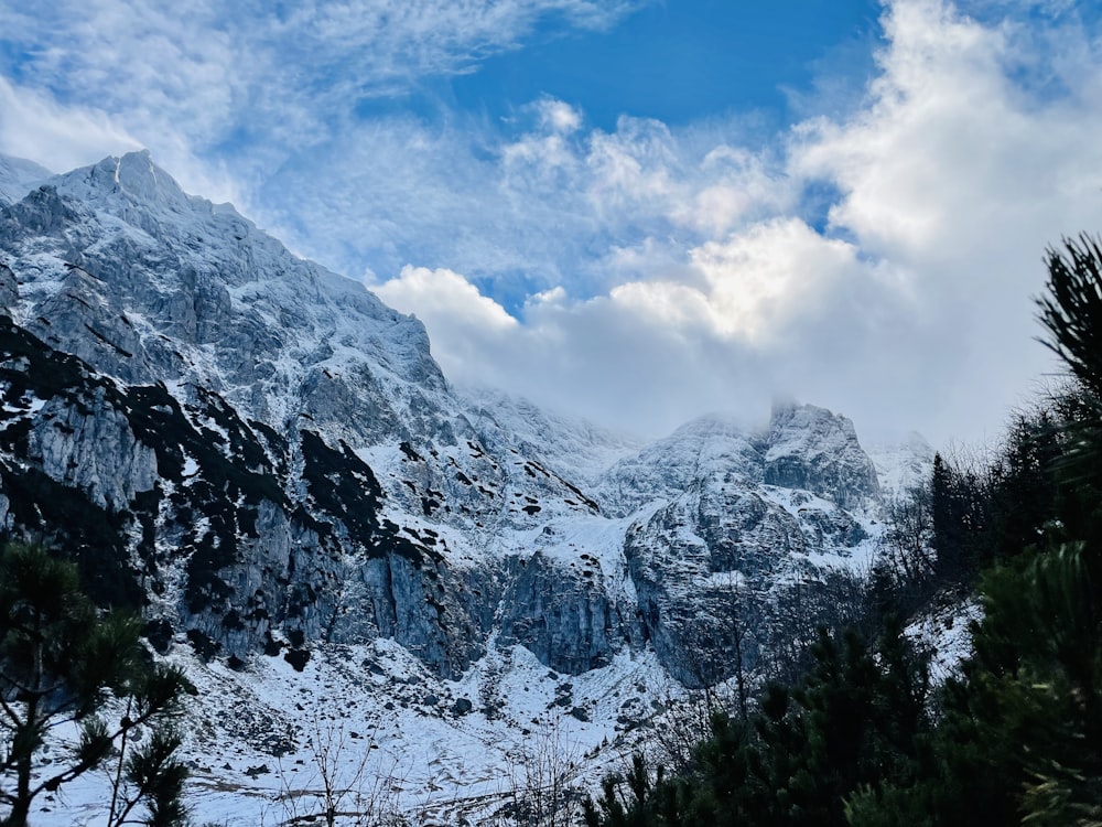 a mountain covered in snow under a cloudy blue sky