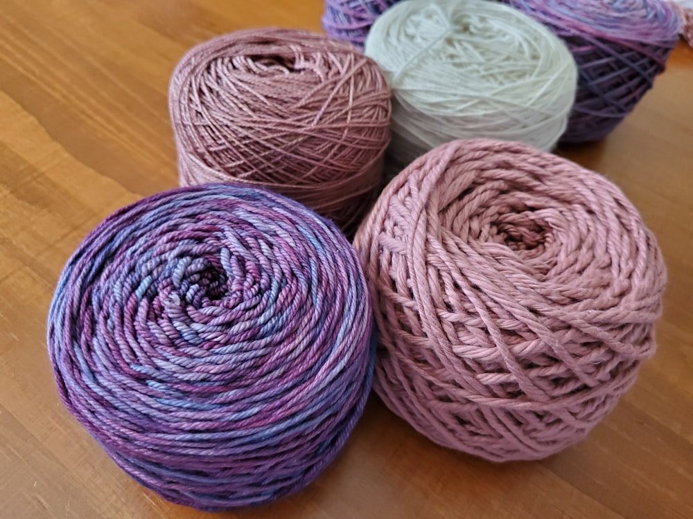 four skeins of yarn sitting on a wooden surface