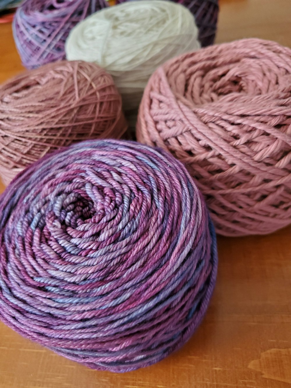 three balls of yarn sitting on top of a wooden table