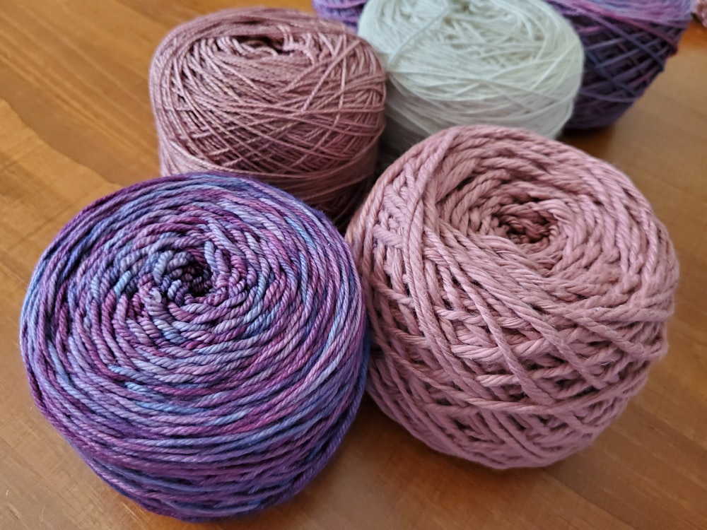 four skeins of yarn sitting on a wooden surface