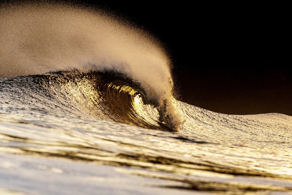 a large wave crashing into the shore of a beach