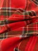 Close-up of a tartan quilt showing detailed woven patterns in deep reds and greens.