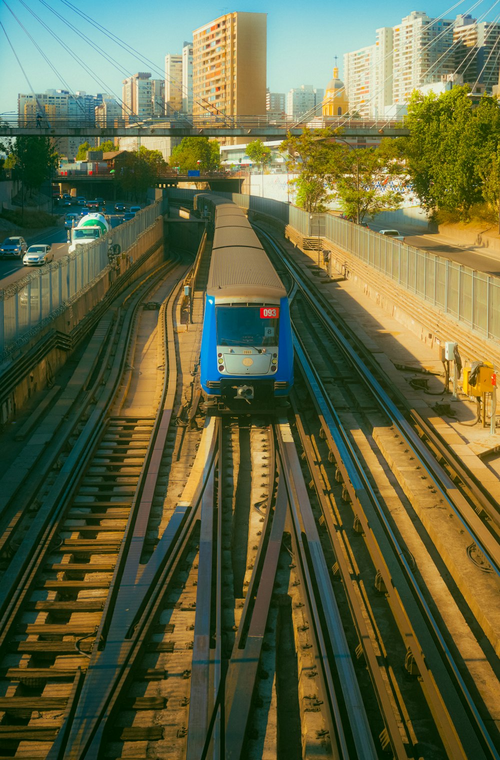 a blue train traveling down train tracks next to tall buildings