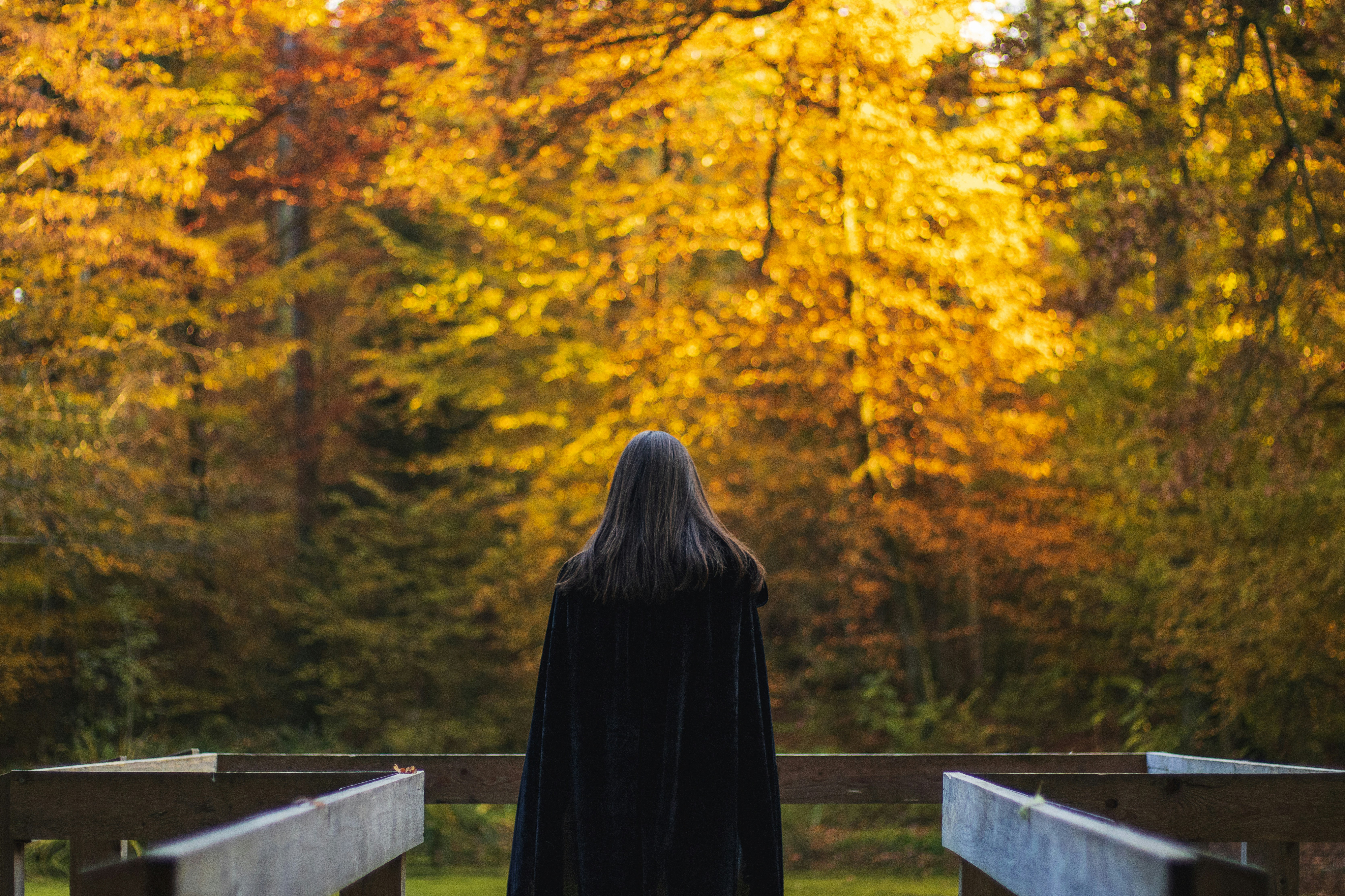 uma mulher em um manto preto de pé em uma ponte