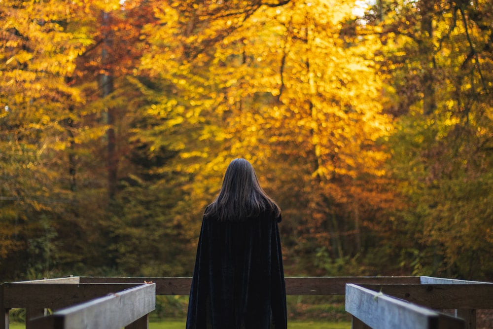 a woman in a black cloak standing on a bridge