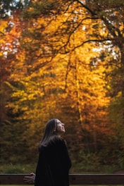 A serene portrait of a woman in nature, reflecting and smiling peacefully.