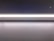 A minimalistic and modern light fixture is mounted on a smooth, dark surface. The lighting strip provides a bright, even illumination along its entire length, casting a subtle glow onto the surface below.