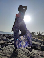 Evening beach scene with a model silhouetted against a colorful sunset, swimwear catching the warm glow.