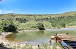 a body of water surrounded by a lush green hillside