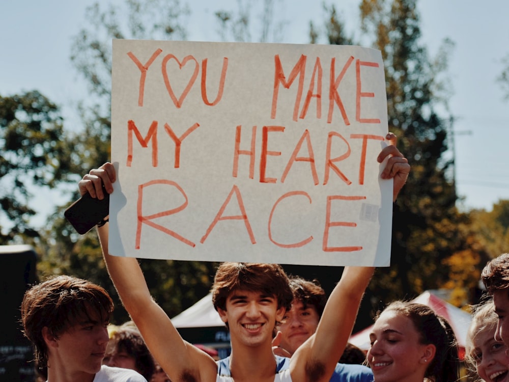 Un hombre sosteniendo un cartel que dice que haces que mi corazón se acelere