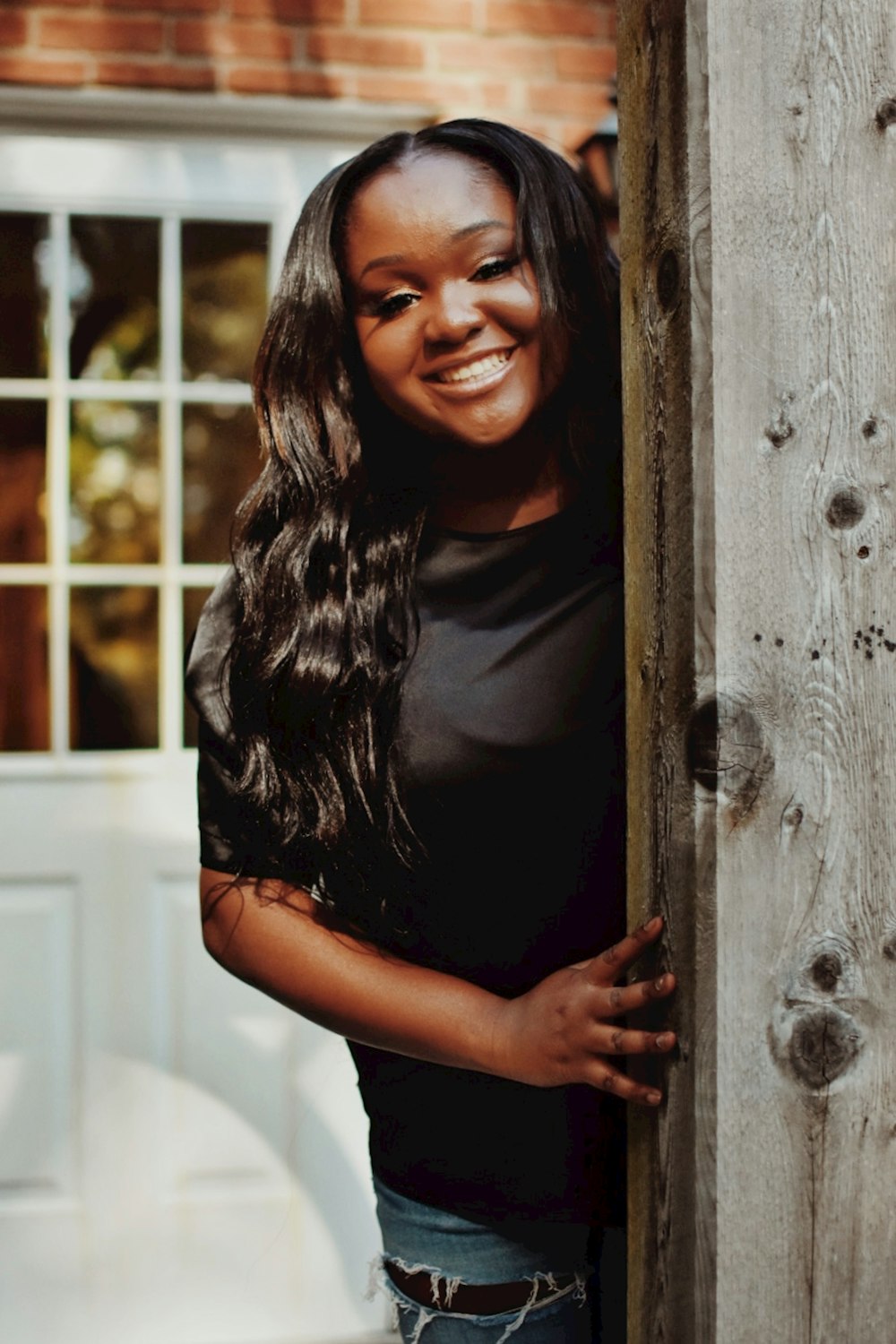 a woman with long hair standing behind a wooden fence