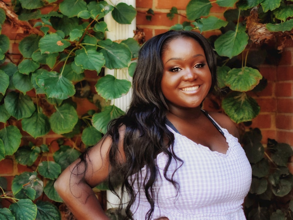 a woman standing in front of a brick wall