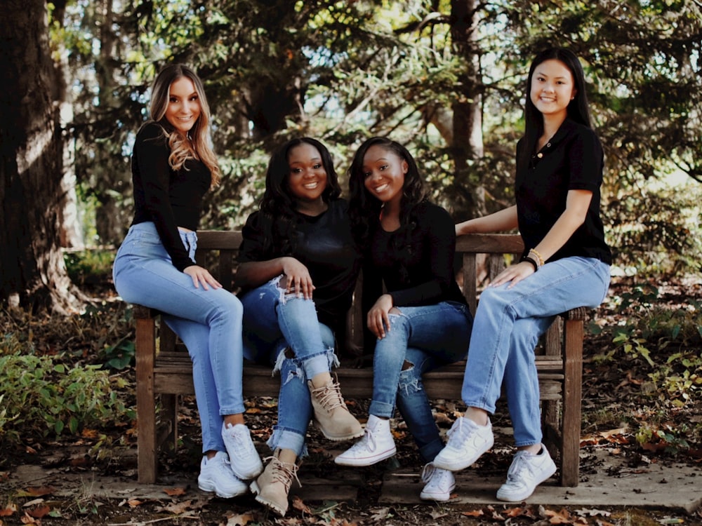 a group of women sitting on top of a wooden bench