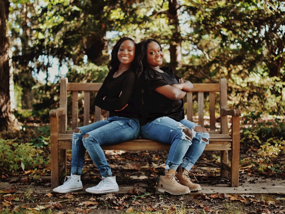 a couple of women sitting on top of a wooden bench