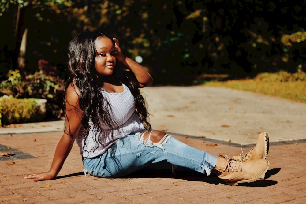 a woman sitting on the ground with her hand on her head