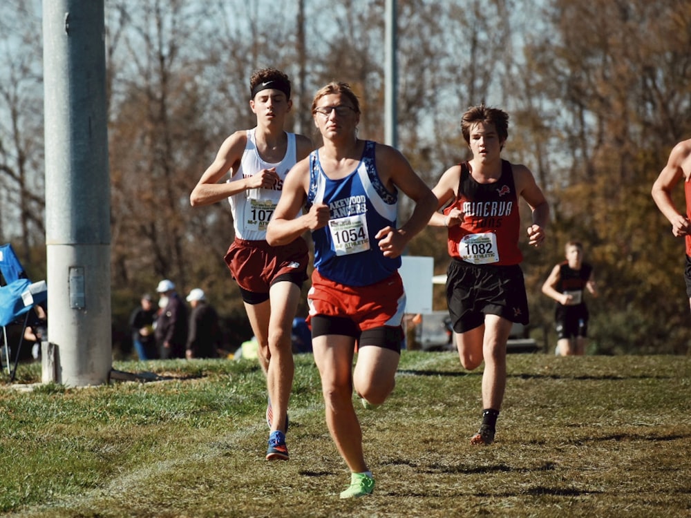 a group of young men running across a grass covered field