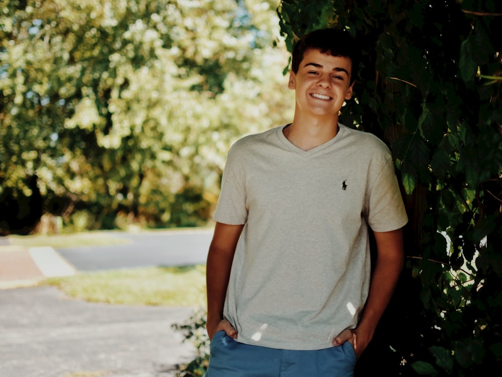 a young man standing in front of a tree