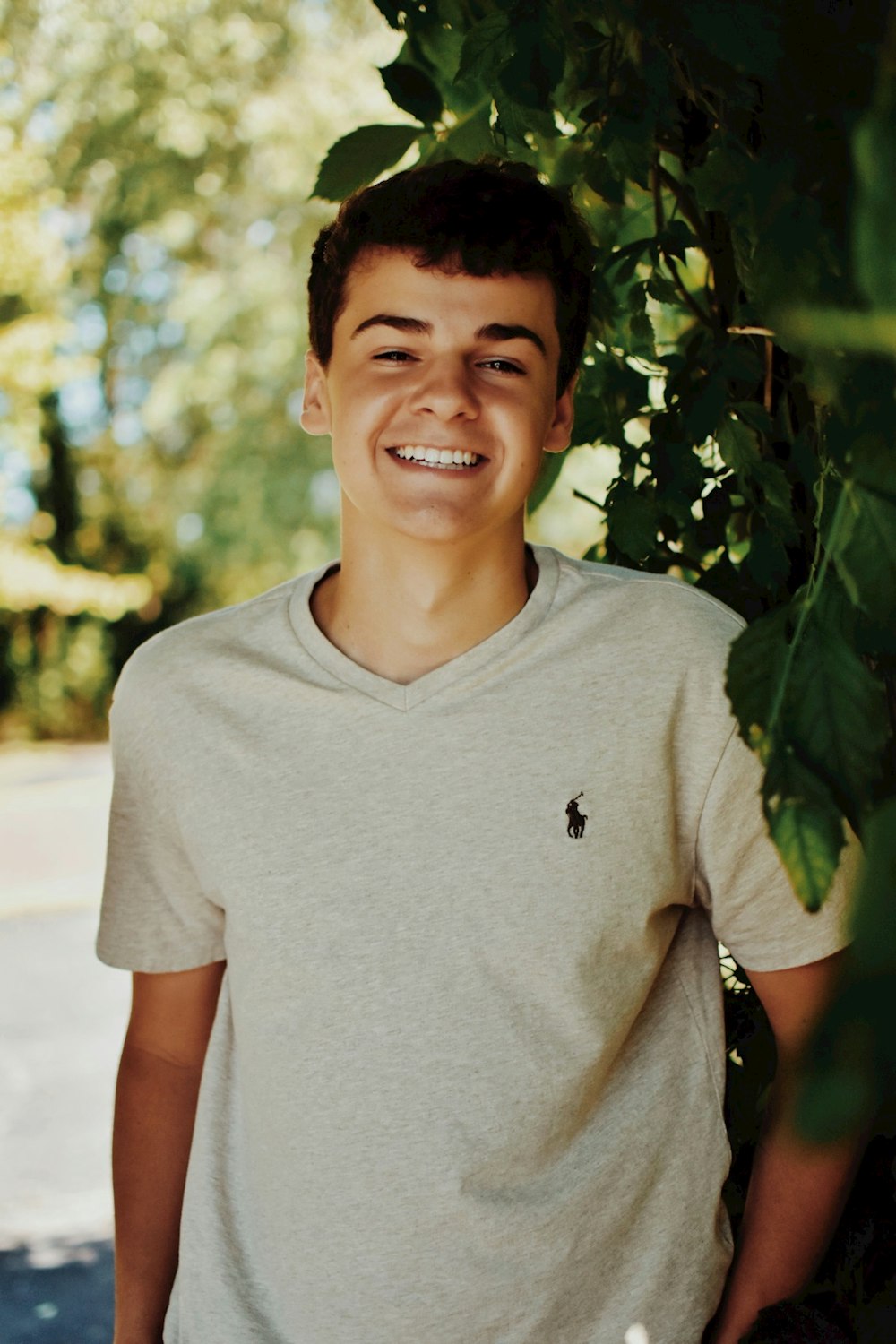 a young man standing next to a tree