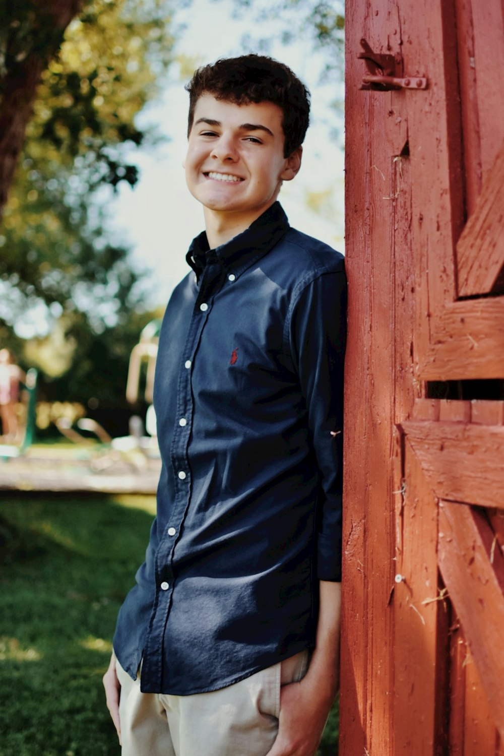 a young man leaning against a wooden fence