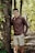 a man standing next to a tree in a forest
