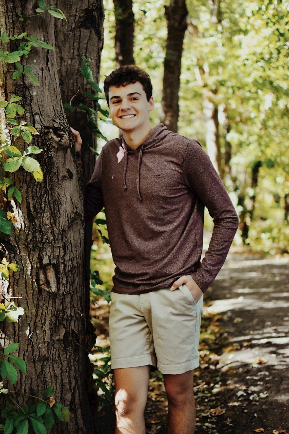 a man standing next to a tree in a forest