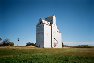 a large white building sitting on top of a lush green field