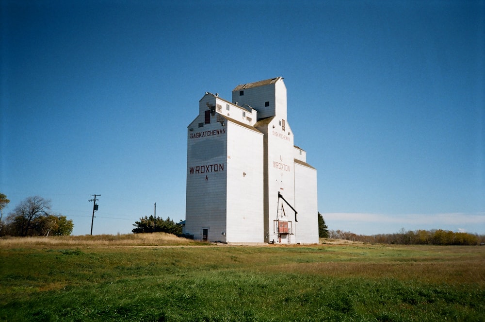 a large white building sitting on top of a lush green field