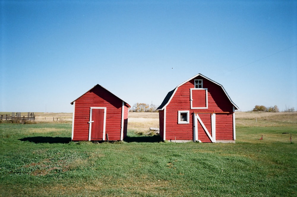 a couple of red barns sitting on top of a lush green field