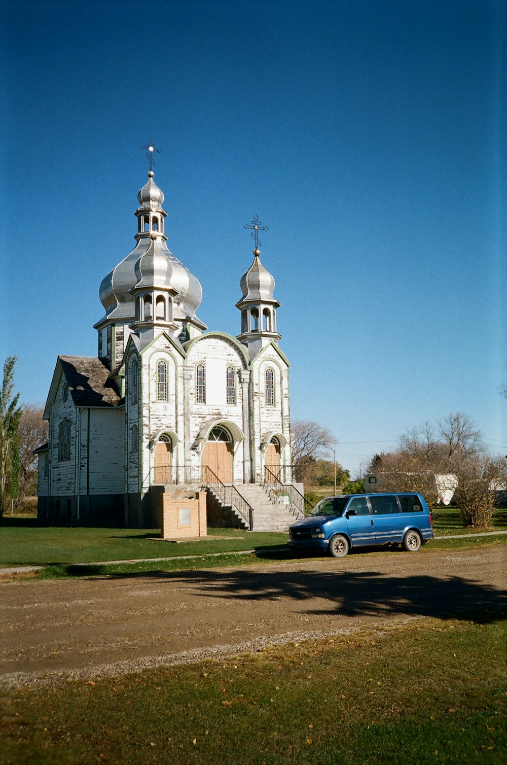 a blue car parked in front of a church