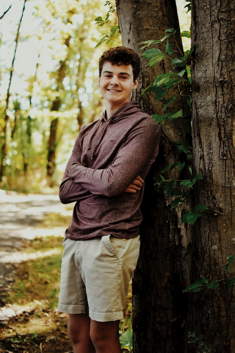 a man standing next to a tree in a forest