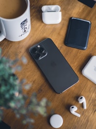 A modern smartphone displayed on a wooden table with accessories around it.
