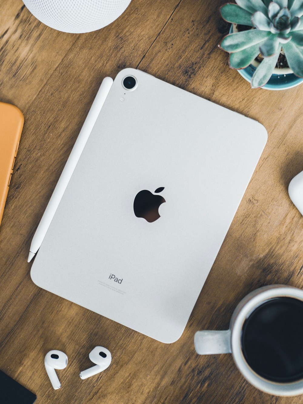 an apple ipad sitting on top of a wooden table next to a cup of coffee