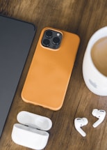 an iphone, earbuds, and a cup of coffee on a table